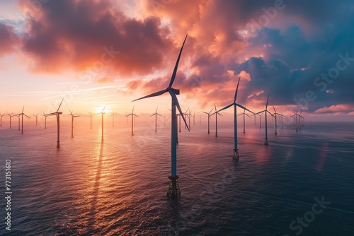 Group of windmills in the ocean at sunset, producing renewable energy with the sun setting behind them
