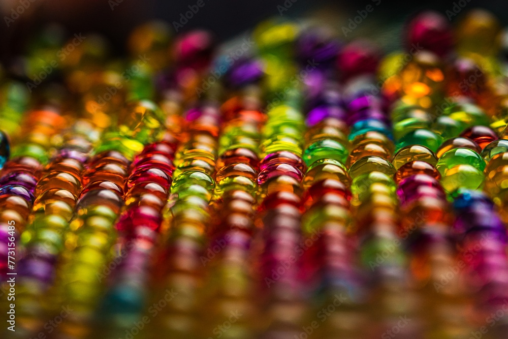 Selective focus shot of some Colorful Water Beads staged in colorful light in close-up