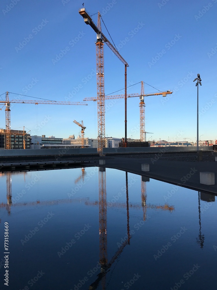 Aerial view of modern buildings and construction cranes with reflection in water
