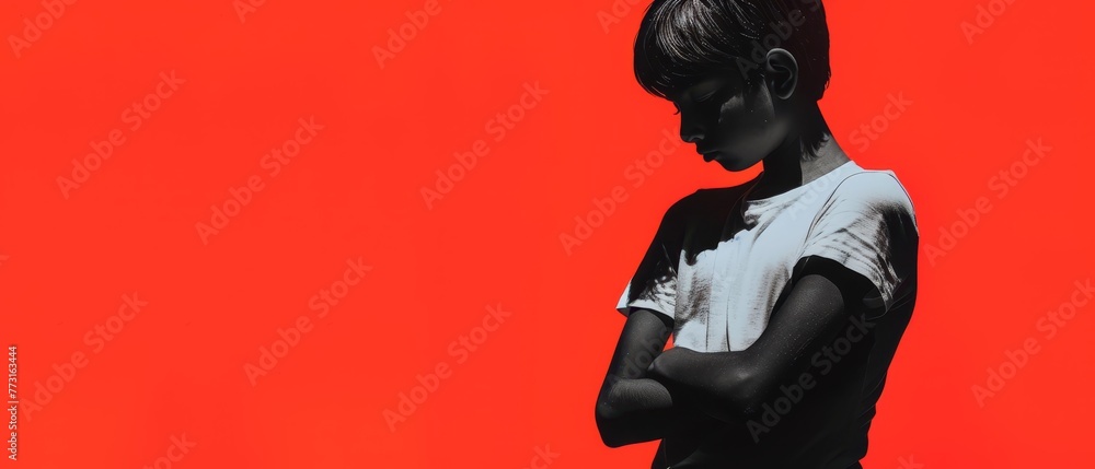 A young boy, hand on chest, gazes at his cell phone against a red backdrop A young boy, hand on chest, gazes at his cell phone against a red backdrop