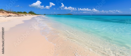  A sunny day at a sandy beach with crystal-clear blue water and a distant hill covered in greenery, topped with fluffy clouds