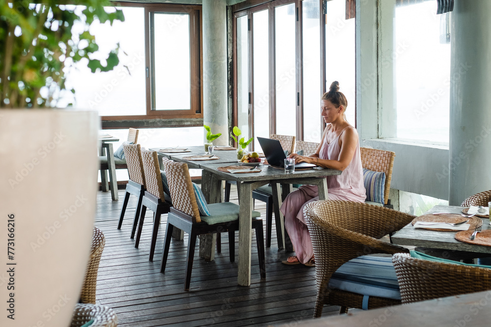 Freelancer Woman Working Remotely on a Laptop in a Modern, Serene Workspace with Natural Light and Comfortable Seating. Freelancer Woman Working Remotely on a Laptop in a Modern, Serene Workspace with Natural Light and Comfortable Seating.