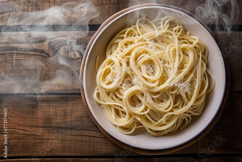 Top-down view of a white bowl filled with steaming spaghetti