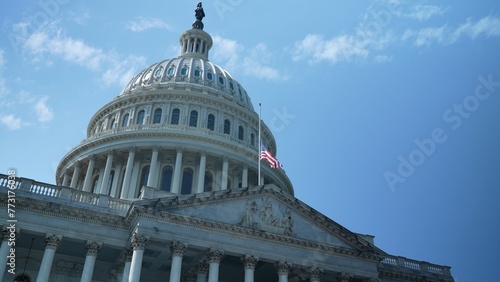 The US Capitol dome with flag at half mast, seat of government in Washington, DC on a beautiful sunny day with clear blue sky.