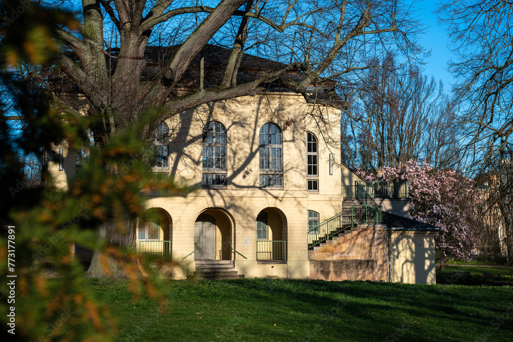 Teahouse in the castle park in Altenburg Thuringia. The teahouse is hidden behind trees. Blooming trees and flowers in the park in spring. Teahouse in the castle park in Altenburg Thuringia. The teahouse is hidden behind trees. Blooming trees and flowers in the park in spring.