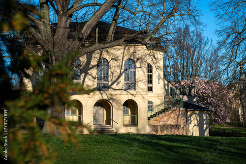 Teahouse in the castle park in Altenburg Thuringia. The teahouse is hidden behind trees. Blooming trees and flowers in the park in spring.