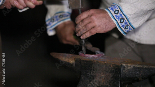 Hands of a blacksmith working on a horseshoe on the anvil