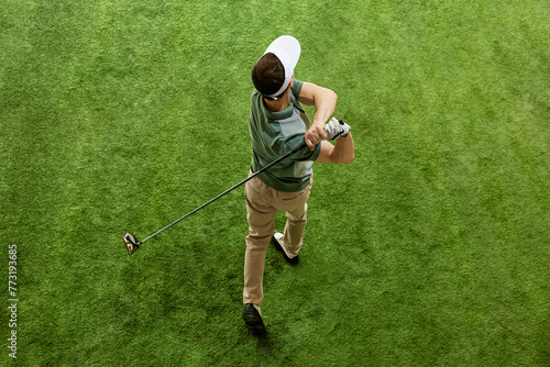 High overhead angle view of skilled golfer in casual attire hitting golf ball on fairway green grass. Concept of professional sport, luxury games, active lifestyle, action. Ad photo