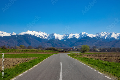 Beautiful landscape with a road leading to the Fagaras mountains with snow on the peaks