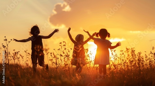 A silhouette of three happy children playing on the field as the sun sets. They are having fun in nature and getting ready to go to school.