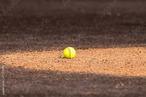 Optic yellow softball on clay pitchers circle with brown synthetic turf  © Thomas