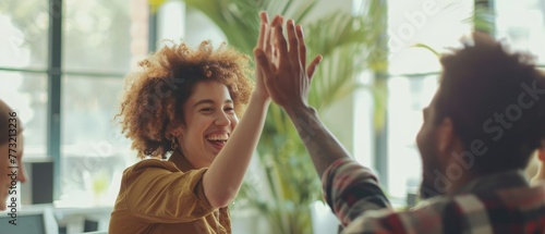 Happy young woman worker giving male colleague high five celebrating good team work results, financial success in professional teamwork at diverse coworkers group office meeting