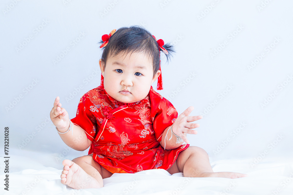 Chinese New Year concept, cute happy little girl in Chinese dress sitting in white living room. Cute Asian baby sitting in white living room, Chinese New Year concept. Chinese New Year concept, cute happy little girl in Chinese dress sitting in white living room. Cute Asian baby sitting in white living room, Chinese New Year concept.
