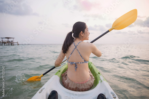 Woman kayaking at sunset sea, kayaking, canoeing, boating. Woman playing on the beach with kayak at the day time. People having fun outdoors. Concept of summer vacation .