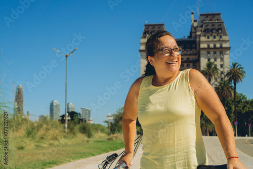 middle-aged latin woman happy with her bike on a sunny day, looking away