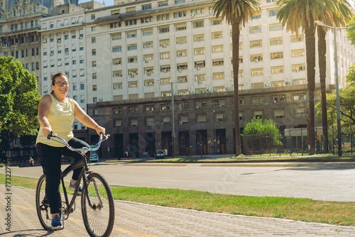 happy middle-aged latin woman riding bicycle in the city