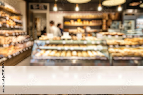 Blurred background of a modern bakery shop interior with a counter and display case full of delicious pastries, cakes, and breads. Shop staff are working behind the glass cabinet in a blurred motion. © gamespirit