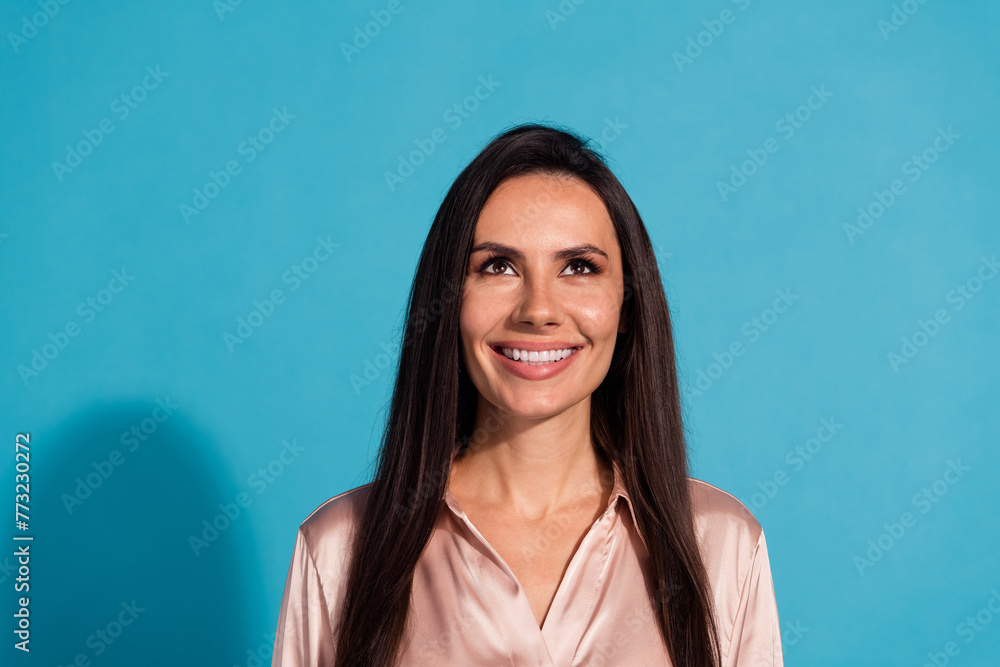 Portrait of lovely gorgeous girl with long hairstyle wear silk blouse look up at sale empty space isolated on blue color background Portrait of lovely gorgeous girl with long hairstyle wear silk blouse look up at sale empty space isolated on blue color background