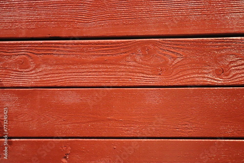 Wooden boards painted red close-up, varnished wood texture. © Marat