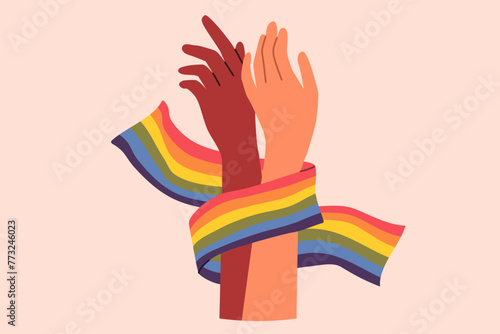 Hands of non-binary couple holding LGBT flag symbolizing love and unity between transgender and gay or lesbian. Pride month concept to promote the idea of tolerance towards LGBT people.