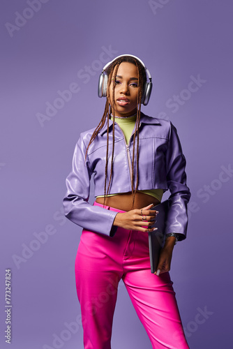 Quadro su tela pretty african american woman with headphones holding laptop and standing on pur