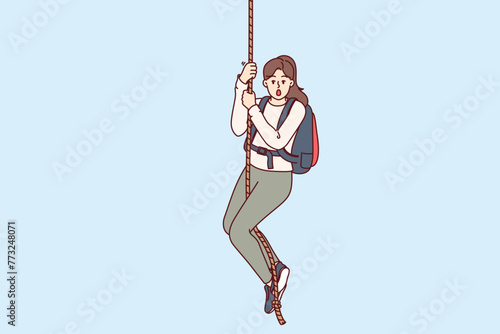 Frightened woman climber hangs on rope and opens mouth from fear, or release of adrenaline in body. Girl engages in extreme sports and is fond of hiking for sake of adrenaline hormone.