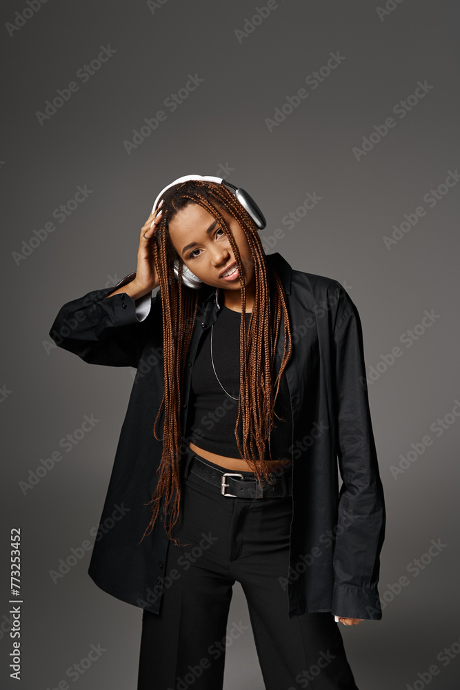 portrait of happy african american girl in dreadlocks listening music in wireless headphones on grey portrait of happy african american girl in dreadlocks listening music in wireless headphones on grey