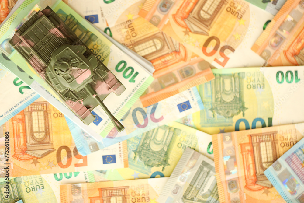 Many euro banknotes and tank. Lot of bills of European union currency and green tank close up Many euro banknotes and tank. Lot of bills of European union currency and green tank close up