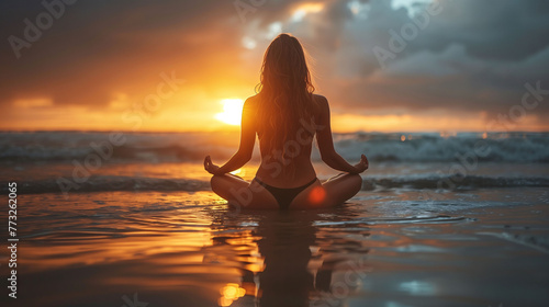 Woman meditating on beach at sunset, serene and peaceful concept. © amixstudio