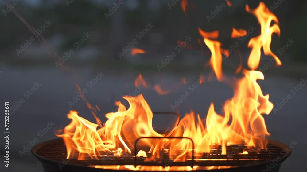 Close up slow motion of charcoal lighter fluid stream add to the fire in a barbecue grill and flame flare strong. BBQ and grilling safety tips Close up slow motion of charcoal lighter fluid stream add to the fire in a barbecue grill and flame flare strong. BBQ and grilling safety tips