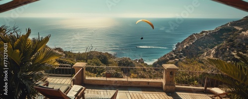 Obraz na płótnie Modern cliffside villa overlooks the ocean with a paraglider soaring by, signifying luxury living and adventure. w salonie