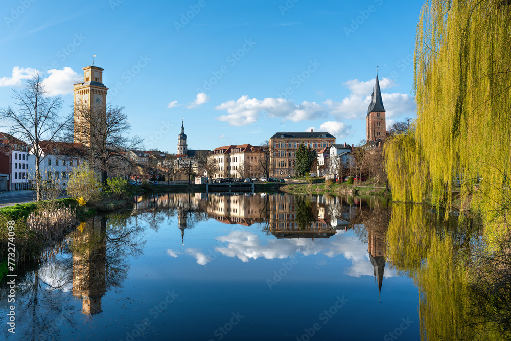 Small pond in Altenburg. Beautiful reflection on the water surface. Art tower, red tips and the tower of the town hall in the picture. Spring weather in Altenburg Thuringia. Small pond in Altenburg. Beautiful reflection on the water surface. Art tower, red tips and the tower of the town hall in the picture. Spring weather in Altenburg Thuringia.