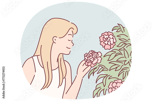 Woman enjoys scent of rose flowers by inhaling scent while walking in park or greenhouse