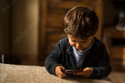 Baby one year old boy touching smartphone at home living room. photo