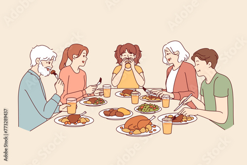 Large family has dinner together after completing religious fast, sitting around table with food. Happy seniors with children and granddaughter having thanksgiving dinner, eating turkey meat