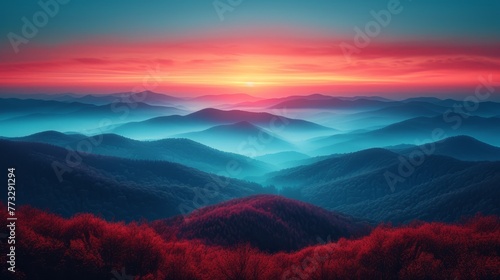   A red-hued forest of trees at the mountains' foot, contrasting against a tranquil, blue sky as the sun sets photo