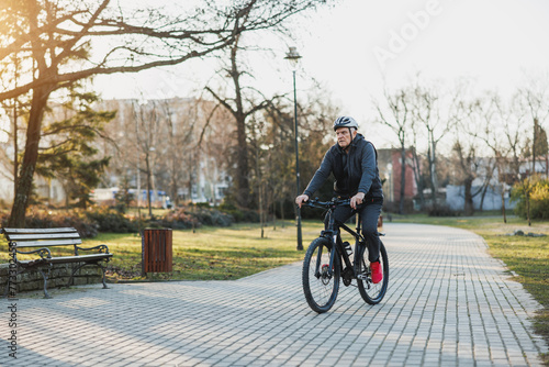 Fototapeta Naklejka Na Ścianę i Meble -  Man Riding Bike Down Brick Road in a Park