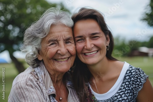 Elderly mother and adult young daughter, smiling and hugging