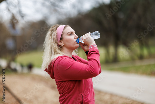 Woman Drinking Water Out of Bottle and Resting After Training Outdoor