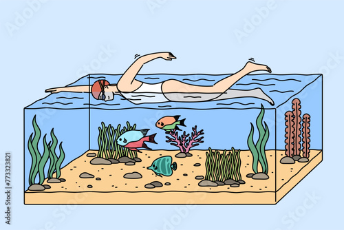 Man swims in tropical sea and dives in large aquarium with fish and underwater plants. Woman in one-piece swimsuit swims in ocean with smile, enjoying active holiday coast of southern island.