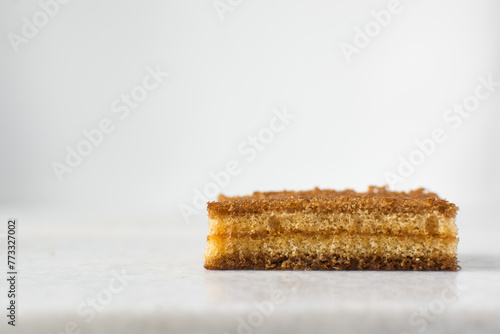 slice of vanilla cake with jam filling, thin layers of vanilla and chocolate cake with jam filling on a white background