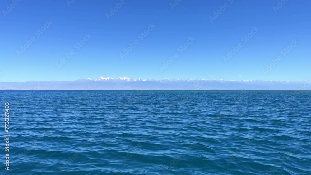 View of Issyk-Kul mountain lake, Kyrgyzstan. Waves splash on a sandy beach with rocks. Calm, peaceful natural background. Lake with a view of the Tien Shan Mountains. Kyrgyzstan 4K View of Issyk-Kul mountain lake, Kyrgyzstan. Waves splash on a sandy beach with rocks. Calm, peaceful natural background. Lake with a view of the Tien Shan Mountains. Kyrgyzstan 4K