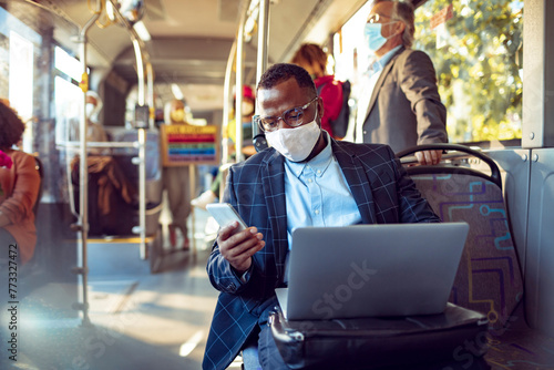 Businessman with face mask working on laptop on public transport photo