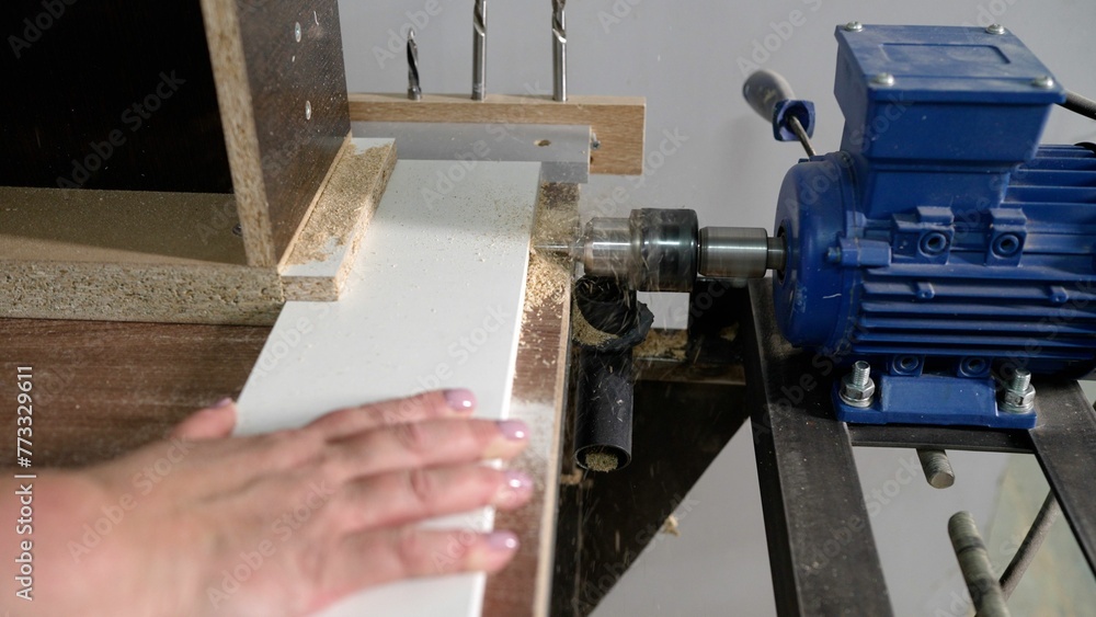 Automatic machine tool makes holes in wooden details of furniture. Furniture production, a machine makes a hole, close-up. Automatic machine tool makes holes in wooden details of furniture. Furniture production, a machine makes a hole, close-up.