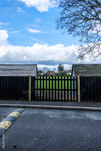 Two Black Painted Wooden Sheds With Metal Fence And Tree