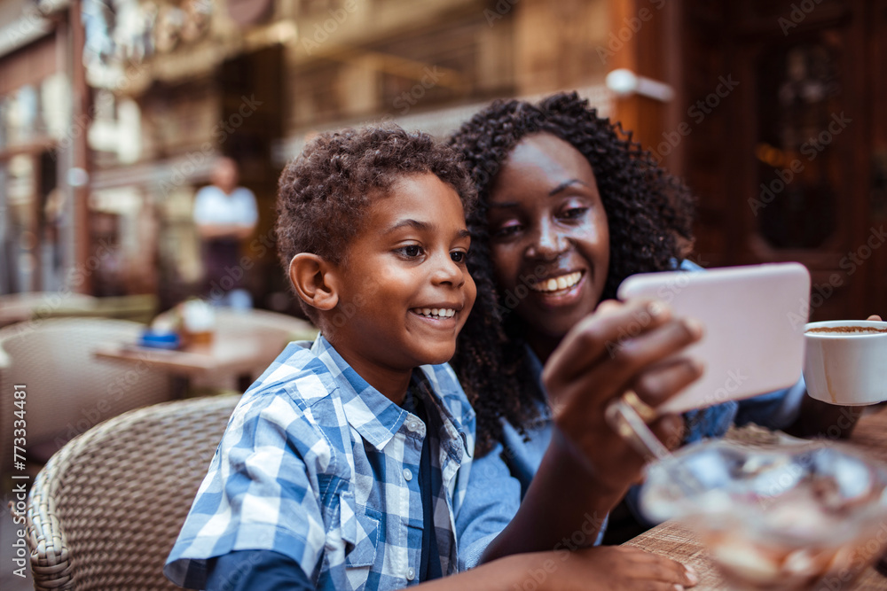Smiling mother sitting in public cafe with son taking selfie Smiling mother sitting in public cafe with son taking selfie