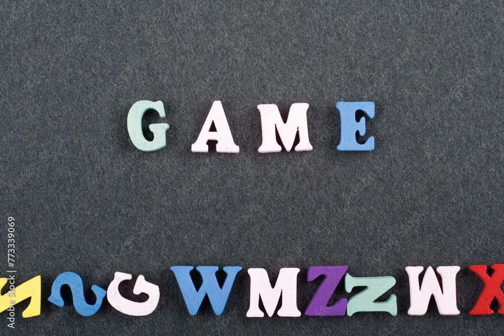 GAME word on black board background composed from colorful abc alphabet block wooden letters, copy space for ad text. Learning english concept. GAME word on black board background composed from colorful abc alphabet block wooden letters, copy space for ad text. Learning english concept.