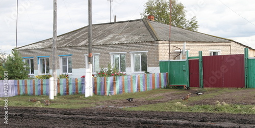 A view of a house with a wooden fence and a duck in summer