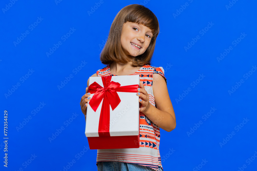 Lovely smiling young preteen child girl kid presenting birthday gift box stretches out hands, offer wrapped present career bonus, celebrating party. Little cute children on studio blue background Lovely smiling young preteen child girl kid presenting birthday gift box stretches out hands, offer wrapped present career bonus, celebrating party. Little cute children on studio blue background