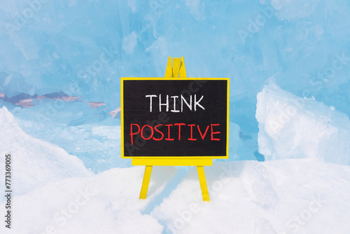 Think positive symbol. Concept words Think positive on beautiful yellow black blackboard. Beautiful blue ice background. Business, motivational think positive thinking concept. Copy space.
